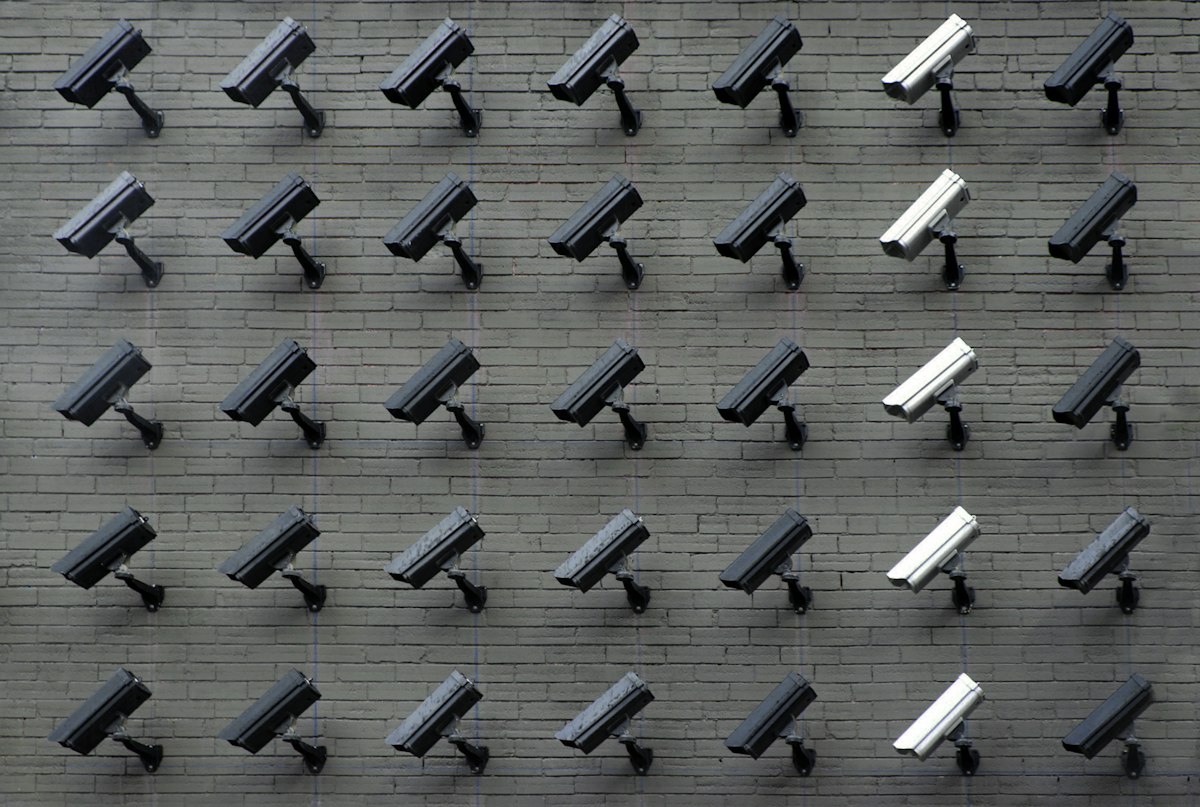Flock Safety Surveillance Camera System Outdoor security surveillance camera mounted on a wall representing Flock Safety surveillance networks and corporate restructuring